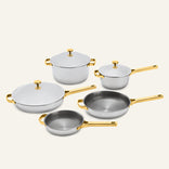 The Titanium Pro Cookware Set+ 2.0 includes five silver-toned titanium pots and pans with gold-colored handles and lids.