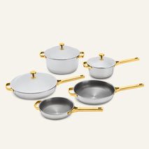 The Titanium Pro Cookware Set+ 2.0 includes five silver-toned titanium pots and pans with gold-colored handles and lids.