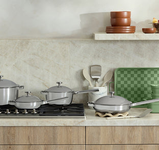 Set of stainless steel cookware on a kitchen counter with a neutral color scheme.