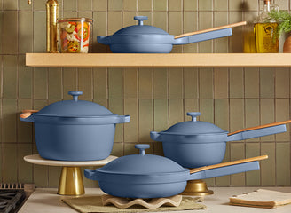 Set of blue cookware on a kitchen shelf with green tiled wall in the background
