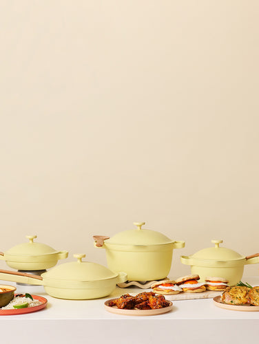 Set of green cookware with food on a beige background