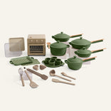 A set of green cookware, a cream oven, and cream accessories on a white background