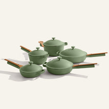 The Cookware Set+ is a five-piece green ceramic set with nonstick pots and pans, each featuring wooden handles and lids, elegantly showcased on a neutral background.