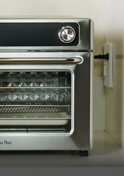 Stainless steel countertop oven plugged into a wall outlet.