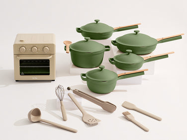 Set of green cookware and white plates on a white background