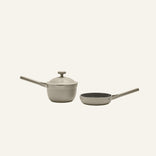 The Tiny Cookware Duo features a beige Perfect Pot with lid and a matching Always Pan, both with long handles and non-toxic coatings, displayed on a plain light background.